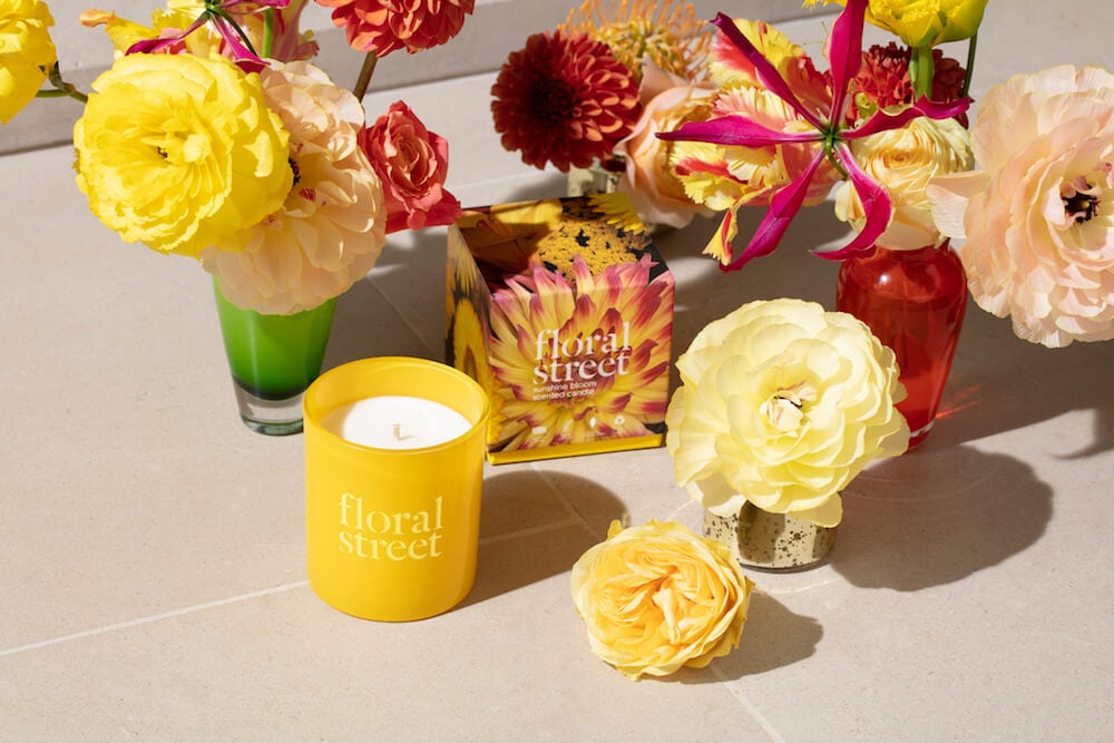 Floral Street candle and packaging shown with fresh flowers