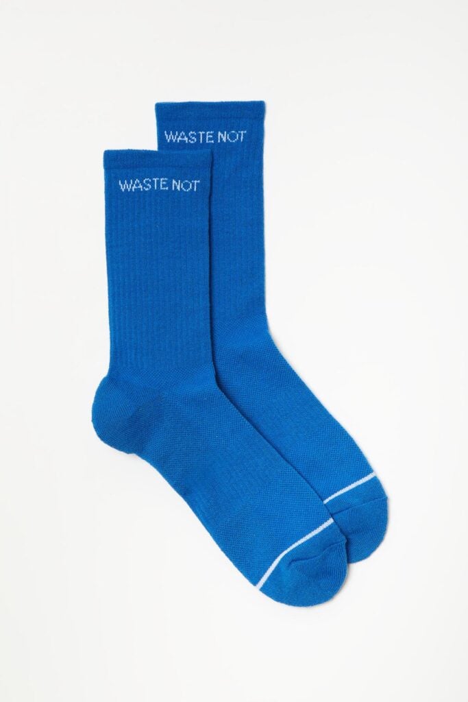 Girlfriend Collective recycled socks in blue featuring the slogan "Waste Not"